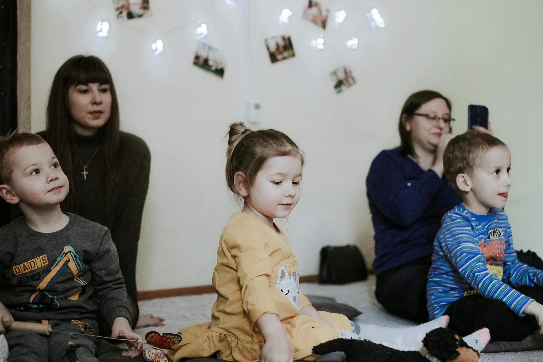Dzieci bawiące się i uczą przy stoliku w przedszkolnej sali z opiekunką