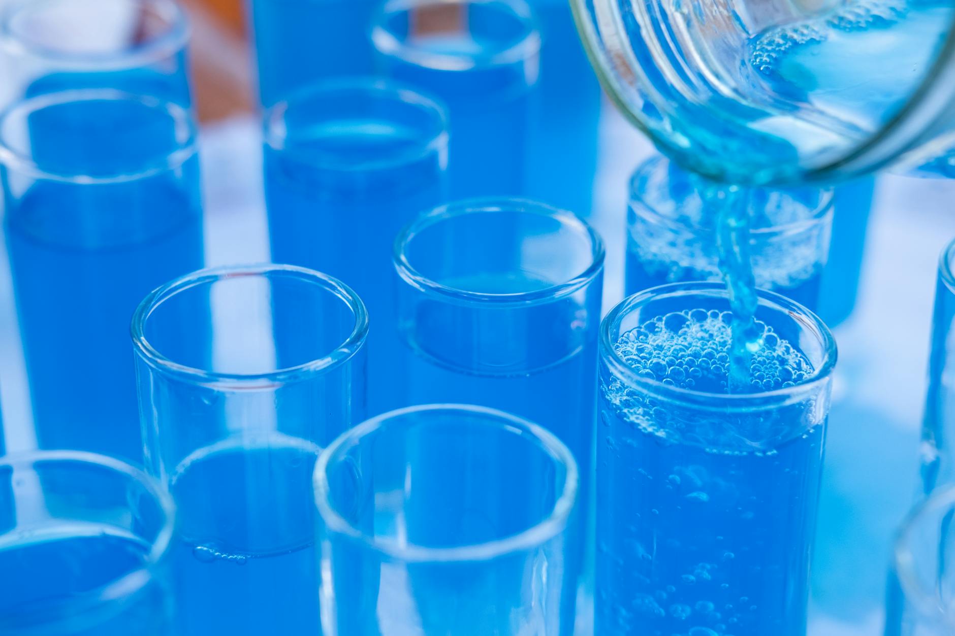Niebieski płyn wlewany do szklanych probówek w laboratorium badania wody