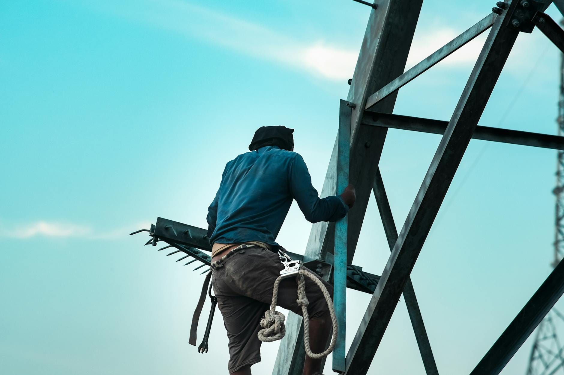 Pracownik budowlany wspina się po stalowej konstrukcji z zabezpieczeniami
