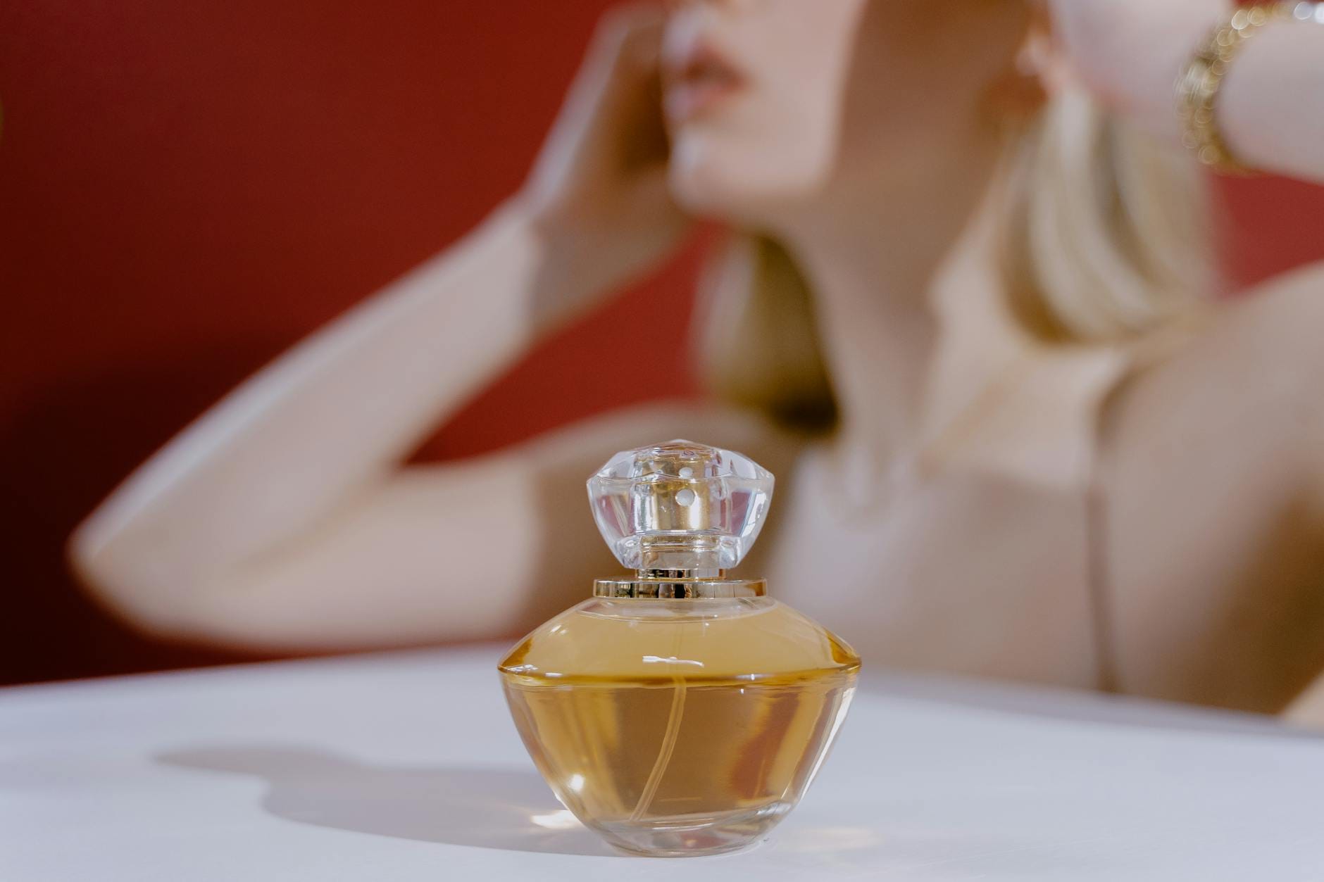 Elegancki flakon perfum na pierwszym planie, rozmyta kobieta w tle