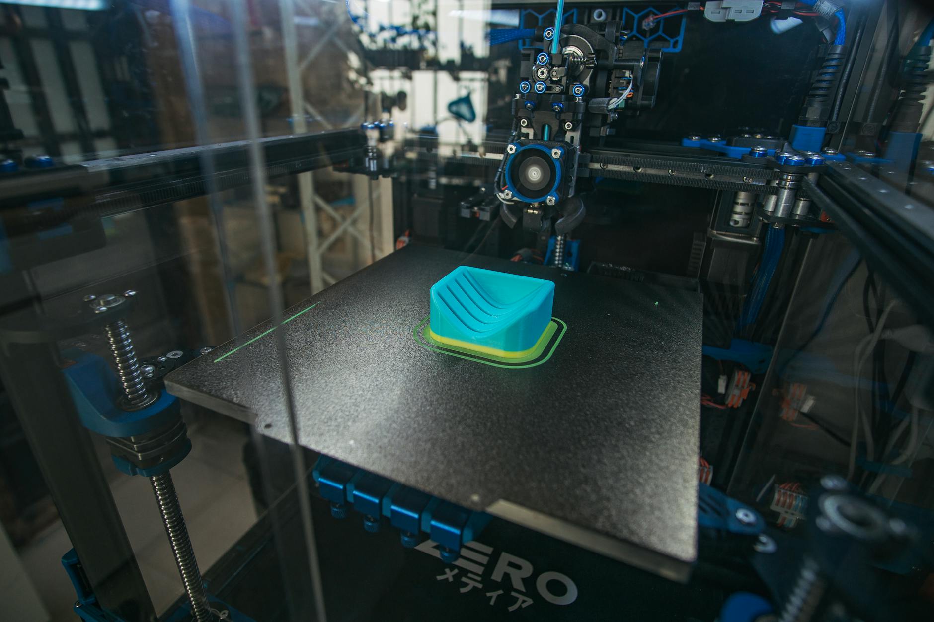 Zbliżenie na drukarkę 3D tworzącą plastikowy element w hali produkcyjnej