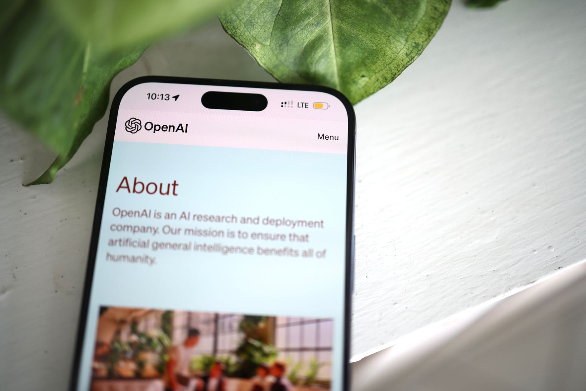 Smartfon z otwartą stroną OpenAI na tle zieleni