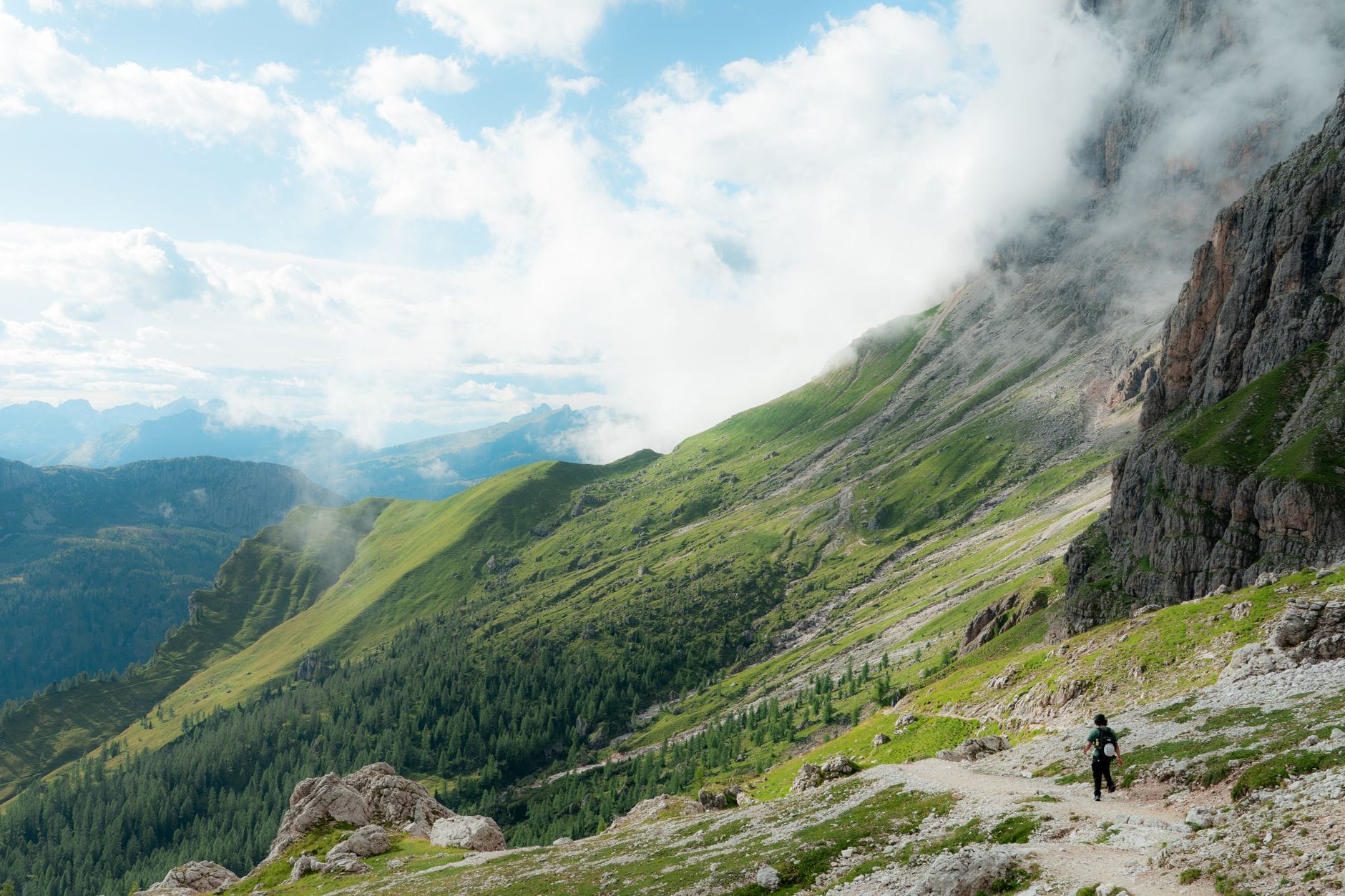Turysta na zielonym szlaku w Dolomitach w otoczeniu chmur